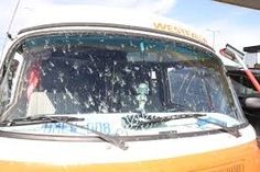 an orange and white van parked in a parking lot next to other vehicles with snow on the windshield