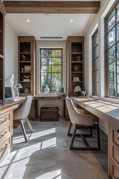 a home office with two desks and large windows