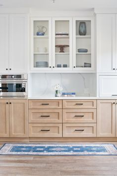 a kitchen with white cabinets and blue rug on the floor in front of an oven