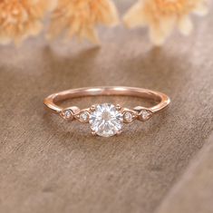 a rose gold engagement ring with an oval cut diamond in the center and three small diamonds on each side