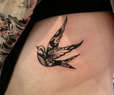 a bird tattoo on the side of a woman's thigh, with an intricate design