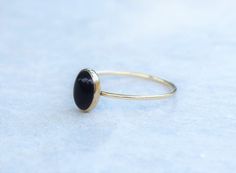 These genuine black onyx gemstones are dramatic and classy. Handset into a delicate 14K yellow gold filled bezel setting. This dainty ring looks gorgeous by itself or stacked with other rings! The deep black onyx gemstone paired with the gold setting creates a stunning and unique look. Setting Details- Material: 14/20 Yellow Gold Filled Band Width: 1mm Gemstone - Gemstone: Onyx Type: Natural Color: Black Size: 8 x 6mm Shape: Oval The ring ships in a custom ring box, ready to give as a gift or ke Black Stackable Rings With Round Band For Gift, Everyday Black Onyx Rings, Adjustable Black Rings For Everyday Wear, Minimalist Black Hypoallergenic Rings, Nickel Free Black Promise Ring, Black Nickel-free Rings For Promise, Nickel Free Black Rings Gift, Nickel-free Black Rings As Gift, Black Onyx Ring Gold