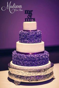 a purple and white wedding cake sitting on top of a table next to a cell phone