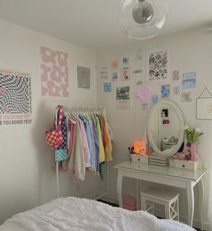 a bedroom with a white bed, desk and mirror on the wall next to it