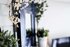 some flowers are in vases on a table near a mirror and window sill