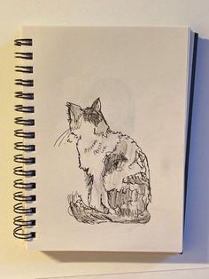 a drawing of a cat sitting on top of a piece of paper next to a pen