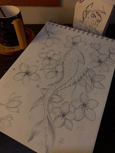 a drawing of a koi fish and flowers on a desk next to a coffee mug