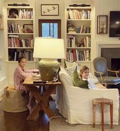 two children sitting on couches in a living room with bookshelves behind them