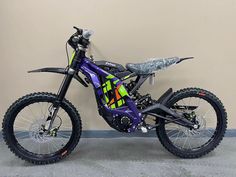 a purple dirt bike parked next to a wall