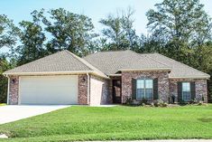 a brick house with green grass and trees in the background