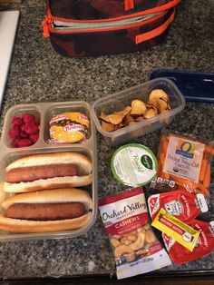 hotdogs, chips, and fruit are on the counter next to a lunch bag