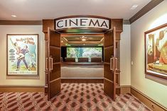 an entrance to a movie theater with posters on the wall and carpeted flooring