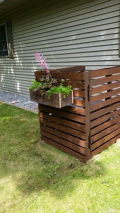 a wooden planter sitting on top of a lush green field next to a house