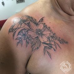 a close up of a person's chest with flowers tattooed on the top of it