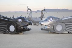 two large metal sculptures in the shape of animals with horns and eyes, sitting on top of each other