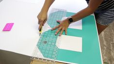 a person cutting out paper on top of a piece of cardboard with scissors and tape