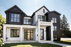 a white and black house with lots of windows on the second floor is featured in this photo