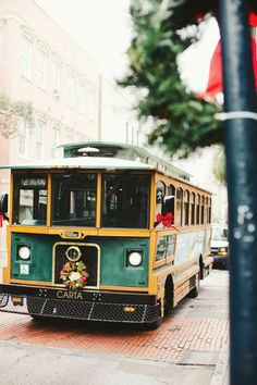 a green and yellow trolley is parked on the side of the street next to a pole