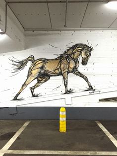 a painting of a running horse on the side of a wall in a parking lot