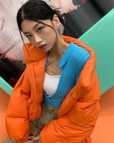 a woman in an orange jacket is posing for the camera