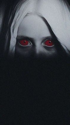 a woman's face with red eyes in the dark