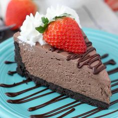 a slice of chocolate cheesecake with whipped cream and strawberries on top, sitting on a blue plate