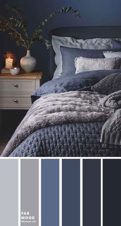 a bedroom with dark blue walls and grey bedding, white nightstands and candles