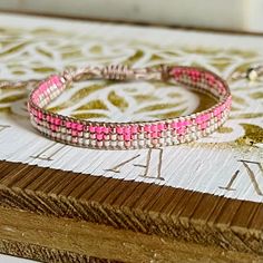 two pink bracelets sitting on top of a wooden table next to an open book