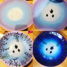 four plates with different designs on them sitting on a wooden table, one is blue and the other is purple