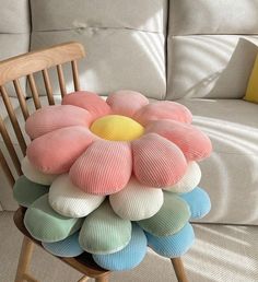 a stack of pillows sitting on top of a wooden chair next to a white couch