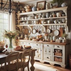 an old fashioned kitchen with lots of plates and pans on the shelves above the table