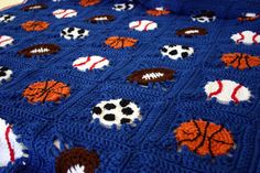 a blue crocheted blanket with sports balls and basketballs on it is shown