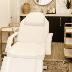 a white reclining chair sitting in front of a mirror on top of a wooden floor