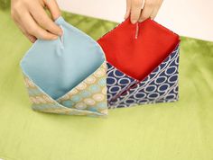 someone is folding an origami box with one piece of fabric in the other