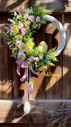 a wreath with flowers hanging on the side of a wooden wall next to a fence