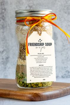 a jar filled with beans and seeds on top of a wooden cutting board next to a tag