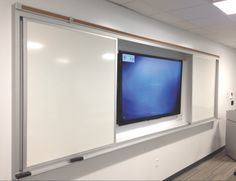 an office cubicle with a flat screen tv mounted on the wall and white cabinets