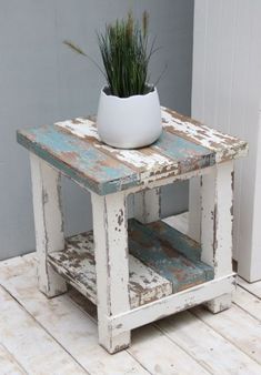 a white potted plant sitting on top of an old wooden table next to a door