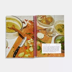 an open cookbook with pictures of food on the table and in bowls next to it