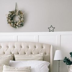 a white bed topped with pillows and a wreath on top of it's headboard