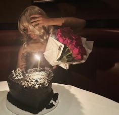 a woman holding a bouquet of flowers in front of a birthday cake