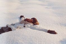 a woman laying in the snow on her back