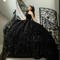 a woman in a black dress is sitting on the stairs