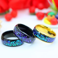 three different colored rings sitting on top of a white table next to red and yellow flowers