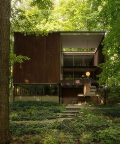 a house in the woods with stairs leading up to it's second story and trees surrounding