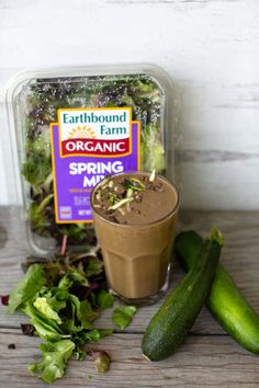 a jar of organic spring mix next to cucumbers