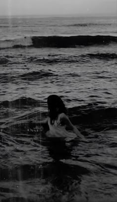 a woman in the ocean with her surfboard under her arm and head above water