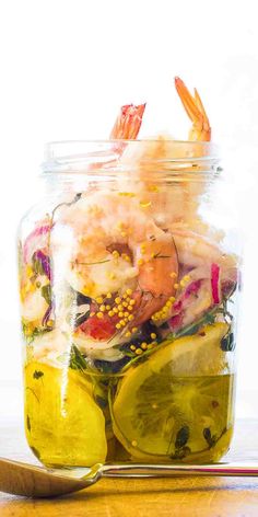 a glass jar filled with shrimp and lemon slices