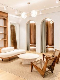 a living room filled with furniture and lots of wooden shelves on the wall next to windows