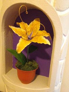 a yellow flower sitting on top of a white shelf next to a potted plant